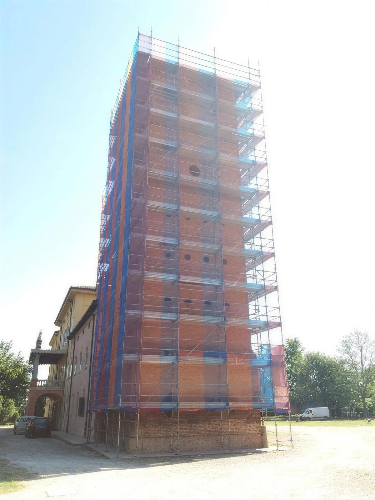 Campanile fasciato dal ponteggio con telo blu e rosso