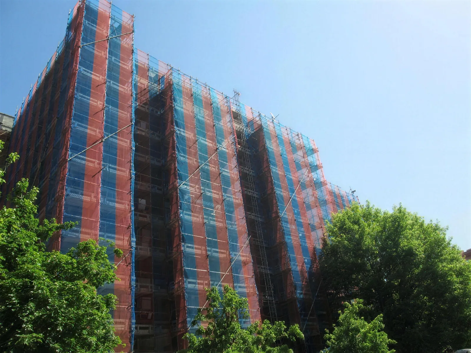 Condominio alto fasciato dal telo a strisce blu e rosse